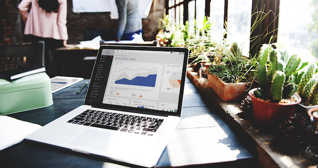 Open laptop on desk with people in the background