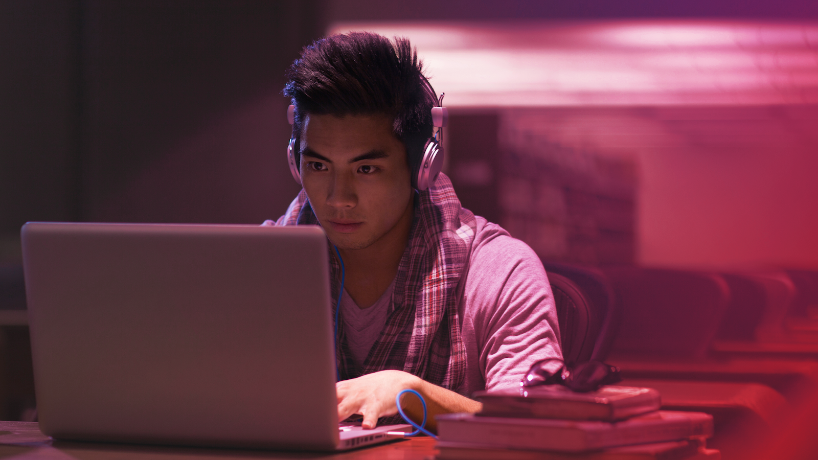 A coding professional works at laptop with headphones