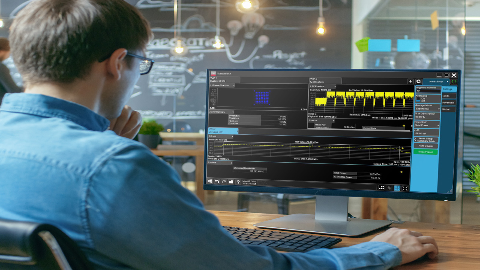 A man views signal analysis software with waveforms and RF measurement data on a desktop monitor.